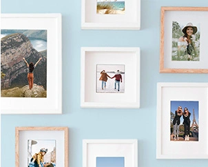 Verschiedene Fotoabzüge gerahmt an blauer Wand hängend